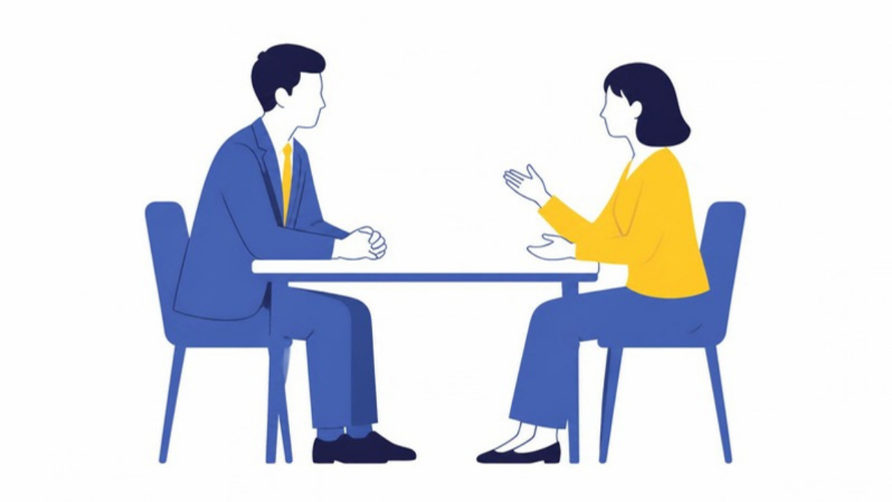 上司と部下が小さな机をはさんで向かい合い、上司がメモを取らずに身を乗り出して、部下の話を聞いている場面